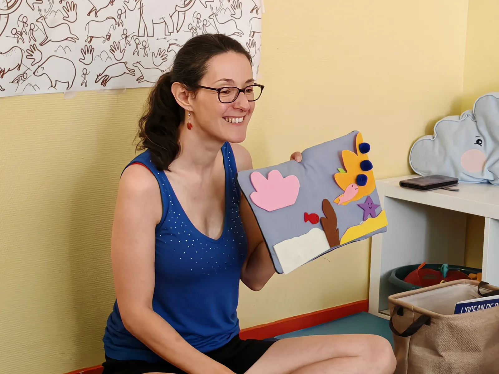 Laetitia Giroud présente un mini-tapis de lecture en tissu, sourire aux lèvres